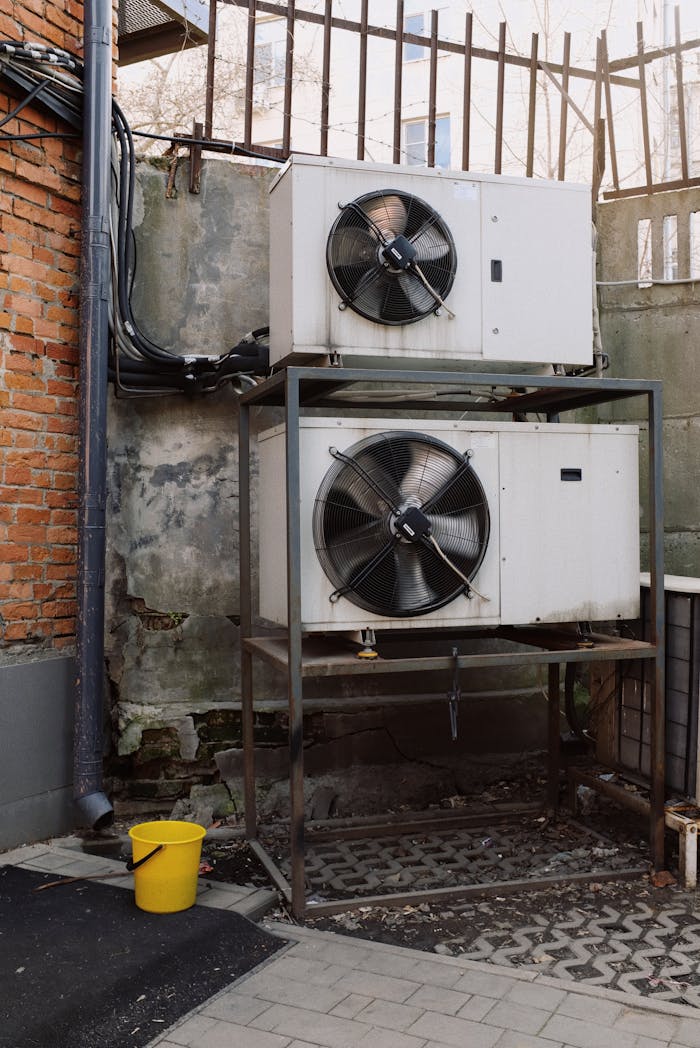 Two industrial air conditioning units mounted outdoors against a brick wall, emphasizing HVAC technology.